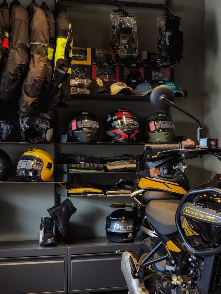 A collection of motorcycle gear including helmets and jackets in a showroom setting.